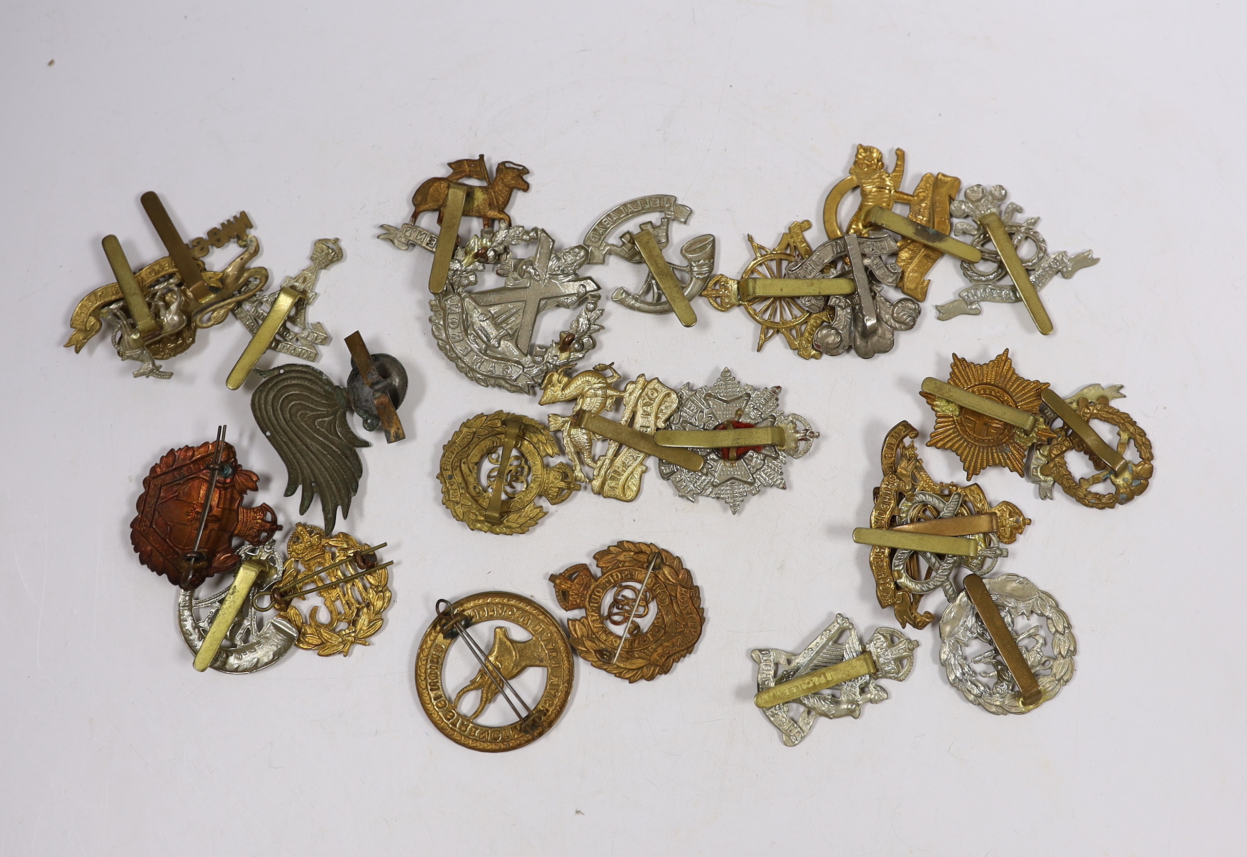 Twenty-five military cap badges including Royal Engineers, The Kings Own, Royal Warwickshire, North Stafford, Royal Berkshire, The Border Regiment, Army Cyclist Corps, South Staffordshire, Middlesex, Cameron, Hampshire,